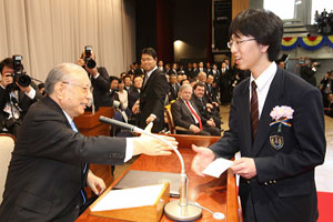 Mr. Ikeda encourages a graduate. During his commencement speech, Mr. Ikeda thanked Soka Schools graduates for studying at the school he founded, asking them to remember to appreciate their parents and develop into worthy individuals who are trusted by others. He advised them to cultivate their character and develop courage to surmount adversities in life, for in the final analysis life is what they themselves make of it. 