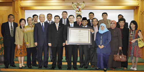Ade Surpriatna, presidente del consejo metropolitano (primer plano, sexto de la derecha) y Hiromasa Ikeda (primera fila, sexto de la izquierda) sostiene el diploma honorario otorgado a Daisaku Ikeda